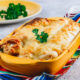 Mexican enchilada in a yellow baking dish on stone background. Selective focus